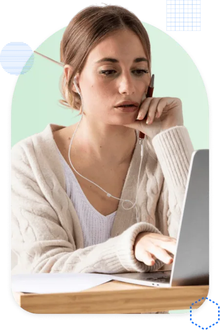 A woman with earphones working at her laptop, deep in thought