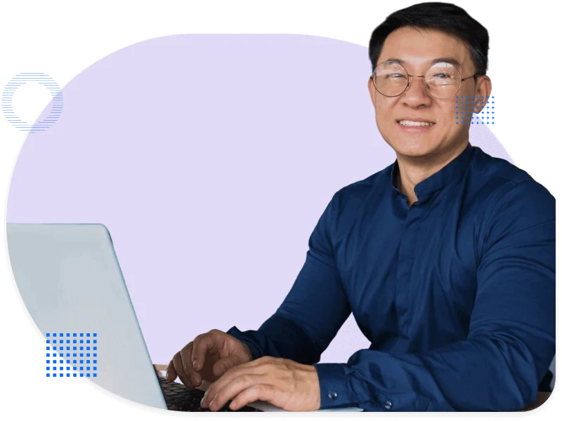 Smiling man in a dark blue shirt working on a laptop, facing the camera – hero image for the manufacturing industry